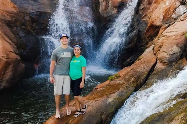 man and woman in front of waterfall