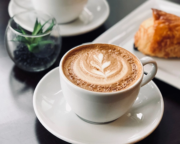 latte on white saucer next to pastry