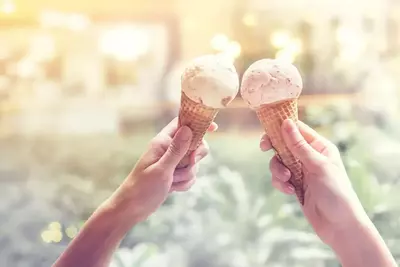 two hands holding up waffle cones with ice cream
