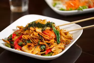 Thai drunken noodles on a white plate with chopsticks