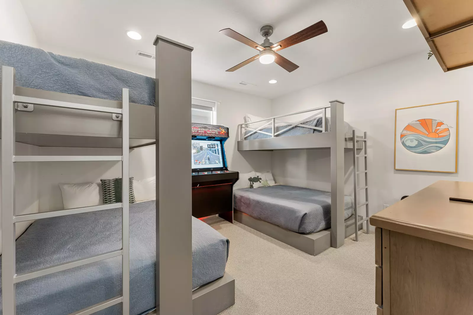 Drift off in your cozy bunk room with plush bedding, ceiling fan, and arcade game for endless family fun.
